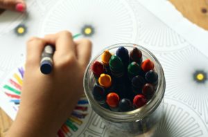 child hands coloring a book, a set of crayons