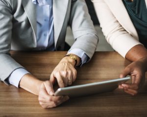 two people working on a grey tablet