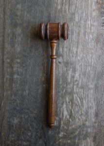 A wooden judge's gavel placed on a textured wooden surface.