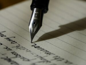 A close-up of a fountain pen writing in elegant cursive on lined paper