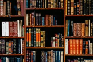 A bookshelf filled with a variety of antique and modern books, featuring ornate bindings and colorful spines