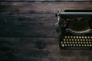 A vintage Corona typewriter on a dark wooden surface.